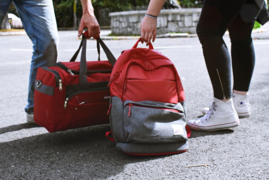 A neutral-colored pair of comfortable walking shoes positioned beside a packed travel backpack, ready for a trip.