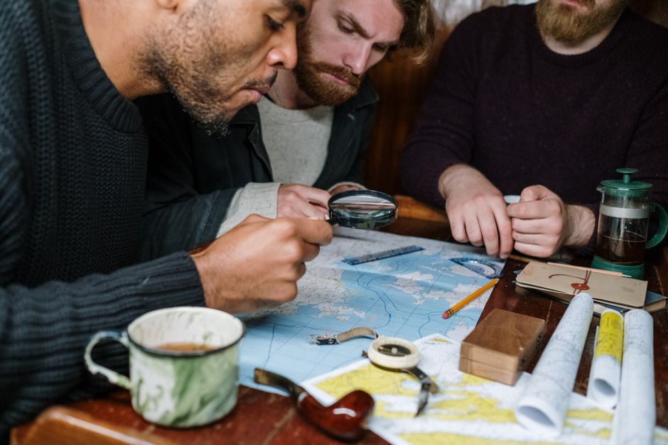 Two individuals gathered around a large map, pointing at destinations and discussing travel plans, representing collaborative and informed decision-making for a trip.