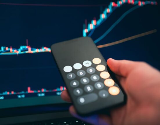 A person's hands holding a smartphone, with a price history graph overlayed on the screen, indicating a price drop for a product.