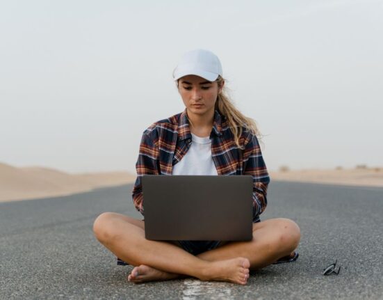 A person comparing flight prices on a laptop screen, showing various airline logos and routes, with a cup of coffee nearby, emphasizing online research.