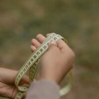A person accurately measuring their foot length and width on a piece of paper with a ruler, preparing for online shoe shopping.