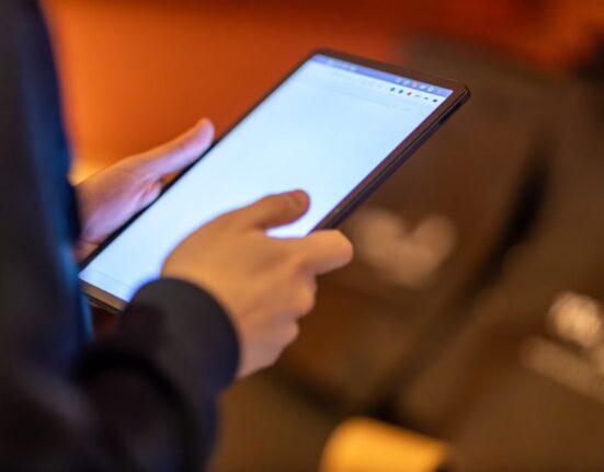 Person browsing smart online deals for gifts on a tablet, looking thoughtful.