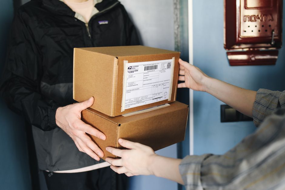 A person smiling genuinely as they unbox a useful gift package, suggesting a successful last-minute purchase that was well-received.