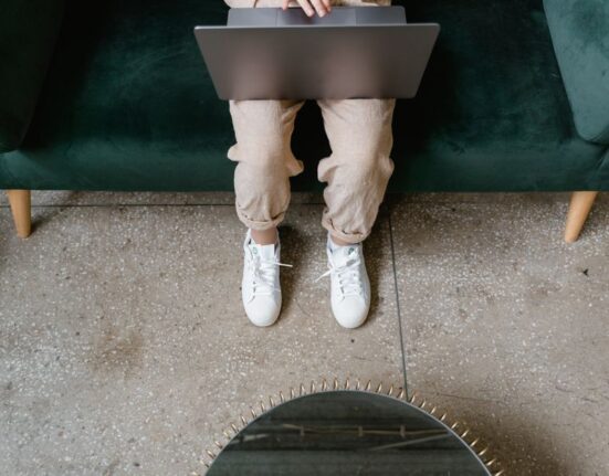 Person standing in a modern, well-cushioned work shoe on a tiled floor, illustrating comfort for long shifts.