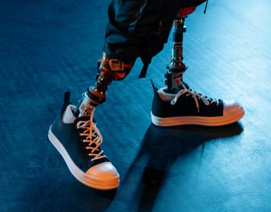 Close-up of a person's feet in comfortable, supportive shoes standing on a tiled floor.