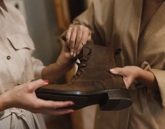 Person sitting in a shoe store trying on a new pair of walking shoes, carefully checking the fit.