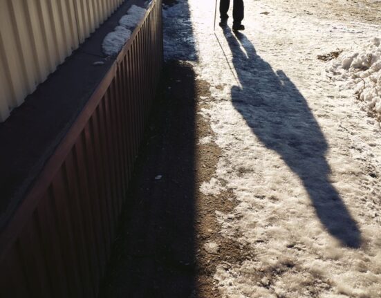 Person confidently walking on an icy city sidewalk, boots visible with good grip.