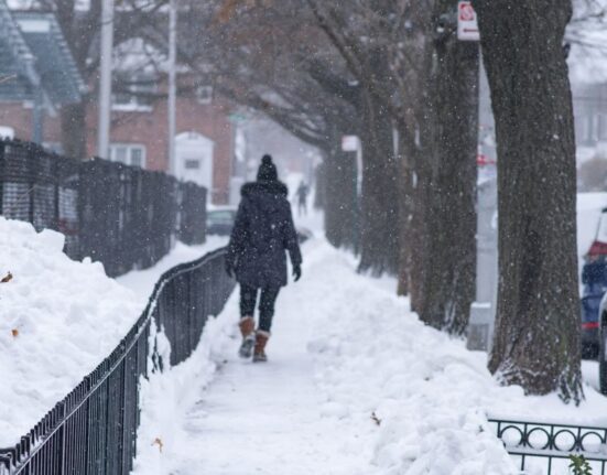 Person confidently walking on a partially icy sidewalk in durable winter boots.