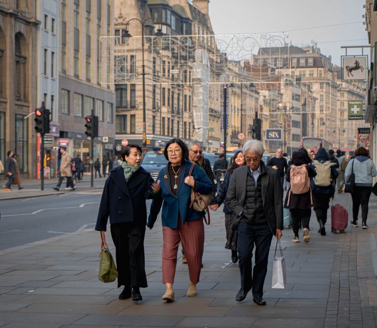 A person confidently navigating a busy pedestrian street in a European city, wearing an anti-theft crossbody bag close to their body, blending in with the crowd.