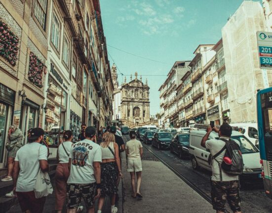 A person wearing a modern anti-theft backpack confidently navigating a bustling street in a European city, with historic buildings in the background.