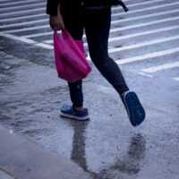 A person in comfortable waterproof shoes walks through a reflection on a wet city street, avoiding puddles.