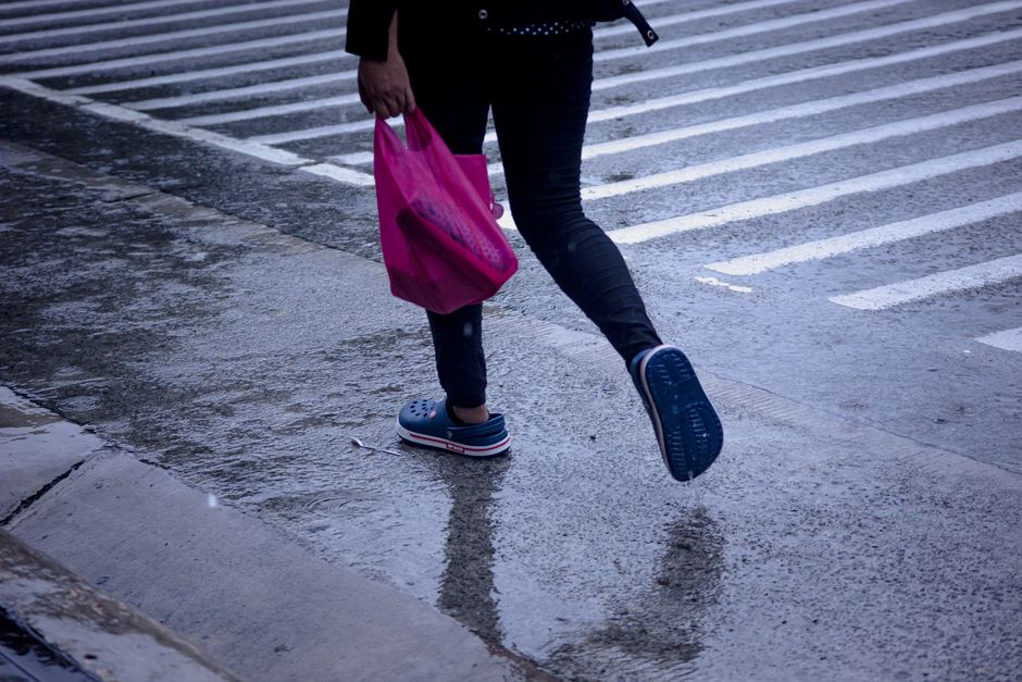 A person in comfortable waterproof shoes walks through a reflection on a wet city street, avoiding puddles.