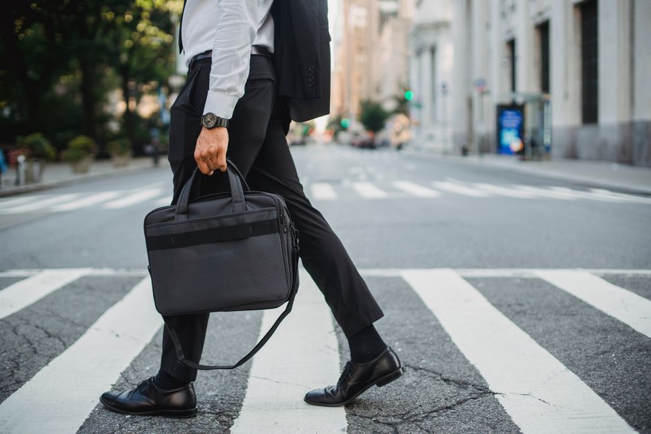 A professional man in a smart casual outfit walking briskly down a city street, showcasing his comfortable office shoes.