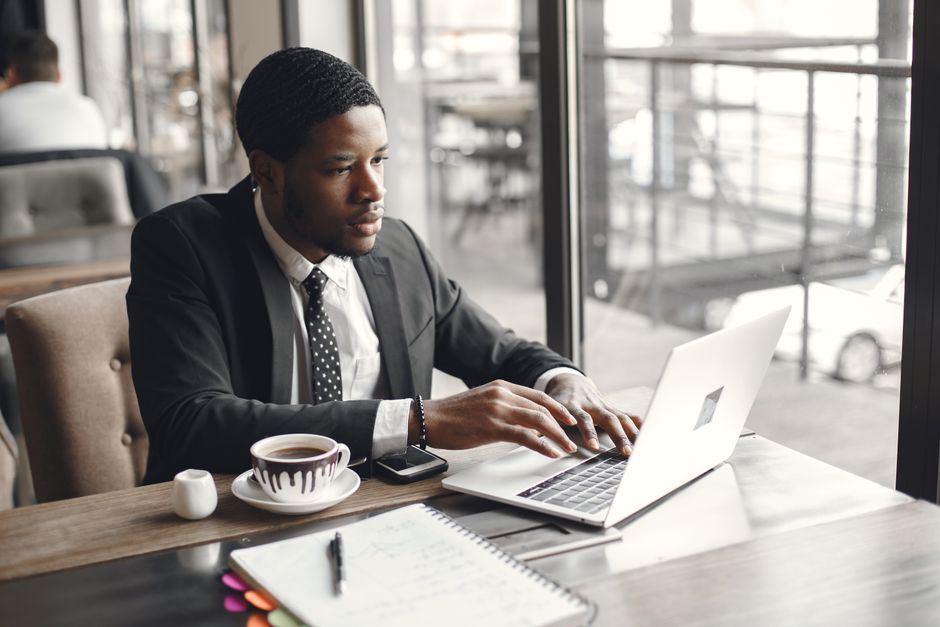 A professional working on a laptop at a cafe table, with a stylish and organized laptop messenger bag next to them.