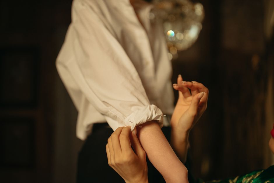 Close-up of a woman adjusting the waistband of her navy tailored trousers, demonstrating a perfect fit with no waist gap, a common solution for achieving comfortable women's workwear.