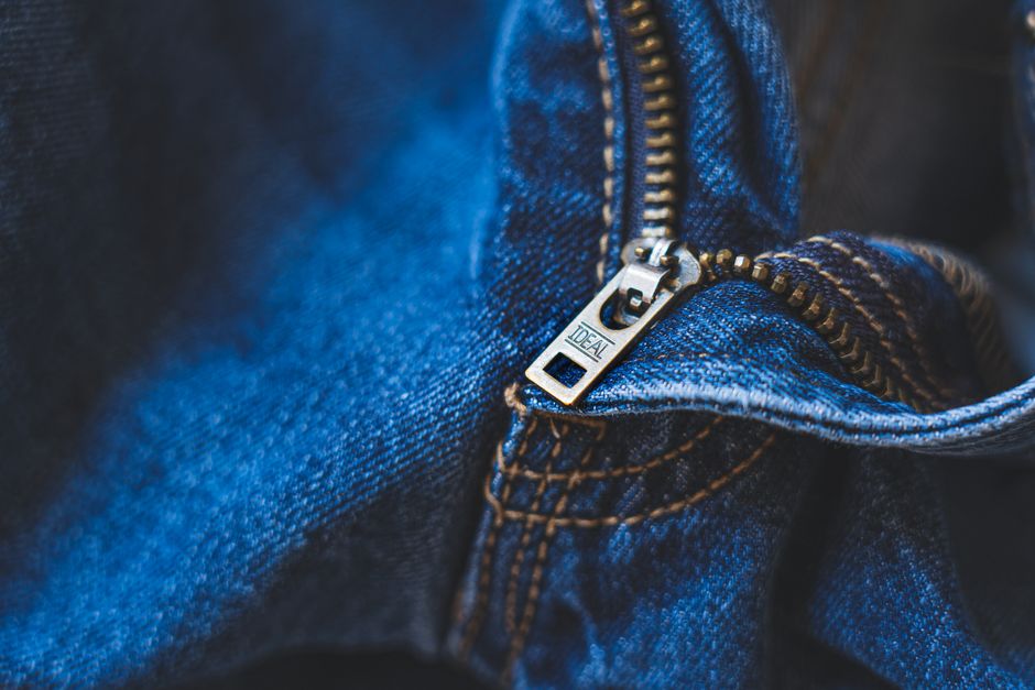 Close-up of a dark fabric carry-on bag showing a metal padlock attached to interlocking zippers and a discreet zippered pocket labeled 'RFID Protected'.