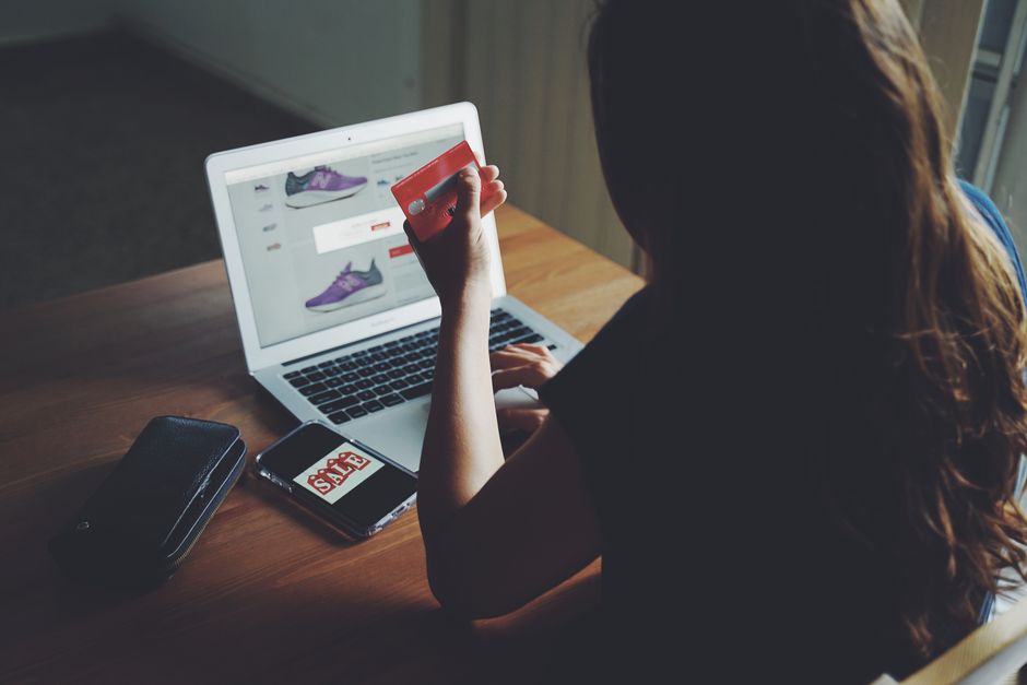 A focused shopper at a desk, looking intently at a laptop screen displaying various online deals and price comparison charts.