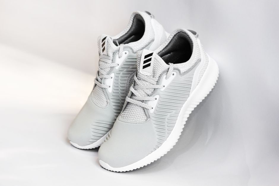 A clean, studio shot showing a running shoe and a walking shoe placed side-by-side on a white surface, highlighting their distinct design features like sole thickness and upper material.