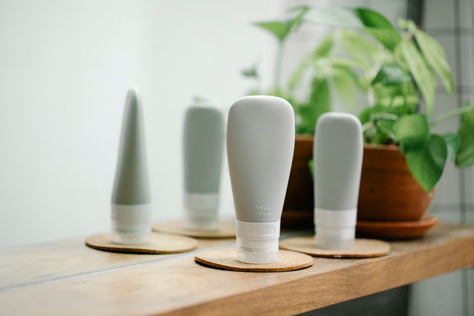 A neatly arranged display of various skincare product bottles, including a retinol serum, moisturizer, and cleanser, on a wooden shelf with soft lighting and a small potted plant in the background, symbolizing a curated beauty routine.