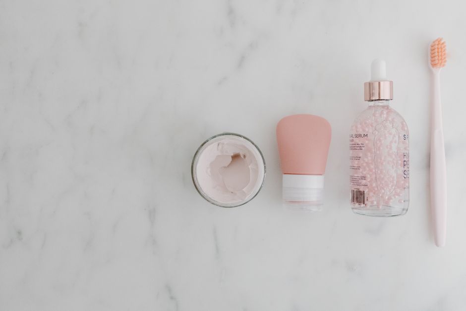 Arrangement of sunscreen bottles, serum dropper, and moisturizer jars on a clean marble countertop, with a modern city skyline subtly visible in the background, representing a practical beauty routine.