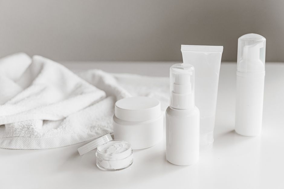 A collection of hydrating skincare products including serums, thick creams, and a cleanser, arranged on a vanity with soft lighting.