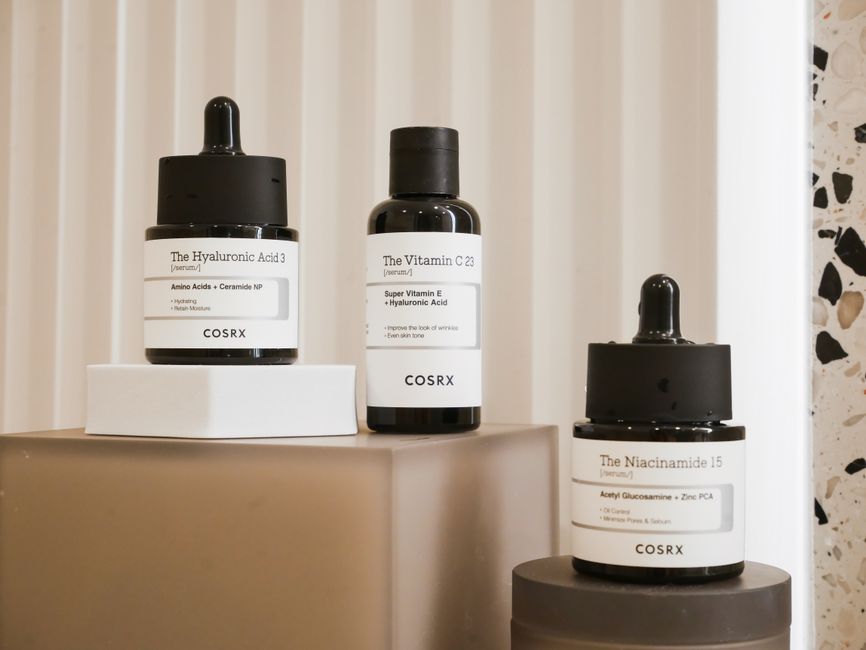 A flat lay of essential skincare products for a beginner retinol routine, including a bottle of retinol, a tube of moisturizer with ceramides, a hyaluronic acid serum, and a bottle of SPF sunscreen, illustrating practical beauty and skincare guide components.