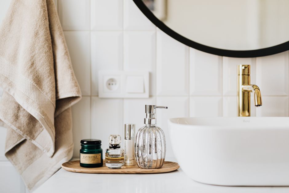 A flat lay of everyday skincare products including a gentle cleanser, hyaluronic acid serum, moisturizer, and a tube of sunscreen, arranged on a bathroom counter.