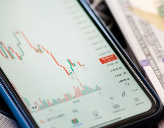 A smartphone screen displaying a price history graph for an online product, showing dips and peaks over time, with a shopping cart icon.