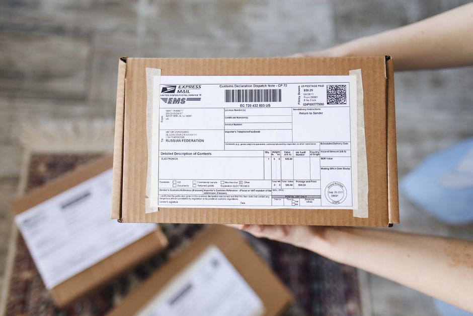 A stack of delivery boxes with diverse shipping labels and customs forms, symbolizing international online shopping and logistics.