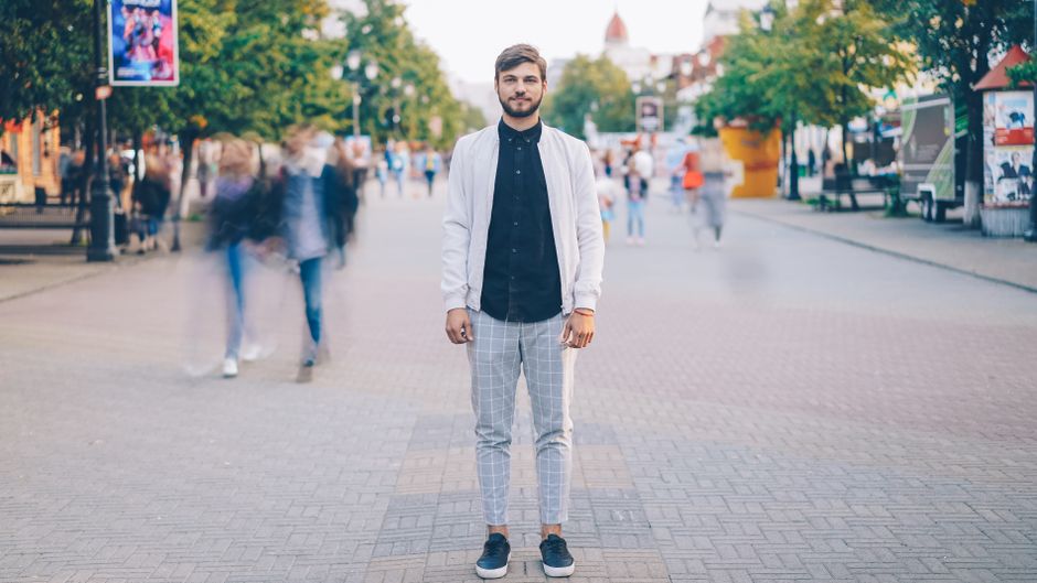 A stylish man in a smart casual summer outfit walking confidently through a European city street, showcasing refined men's summer outfits.