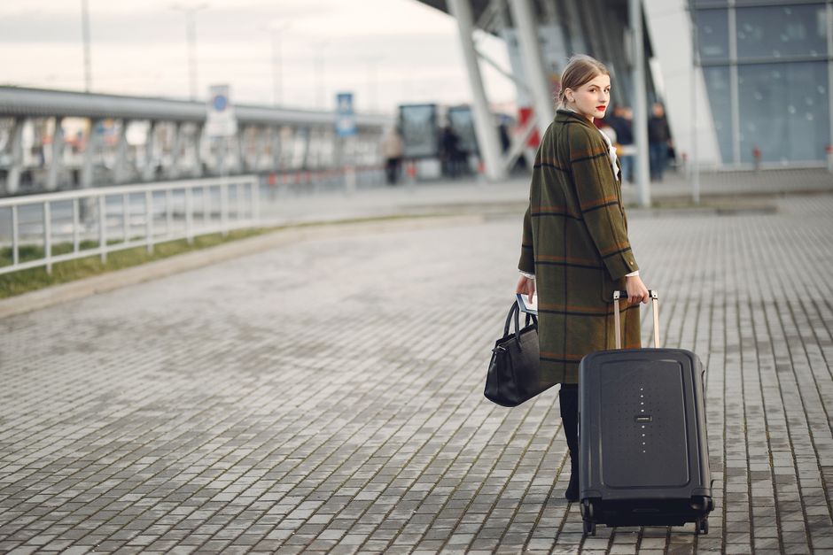 A traveler standing in a bright airport terminal, with a sleek carry-on bag featuring a dedicated laptop compartment, ready for security checks.