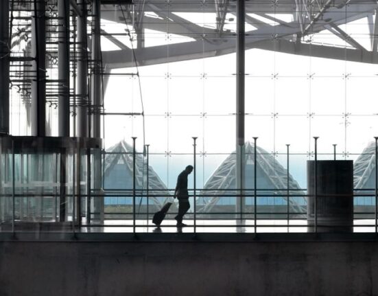 A traveler navigating a busy airport concourse with a soft-sided carry-on suitcase, illustrating the ease of movement with the right bag.