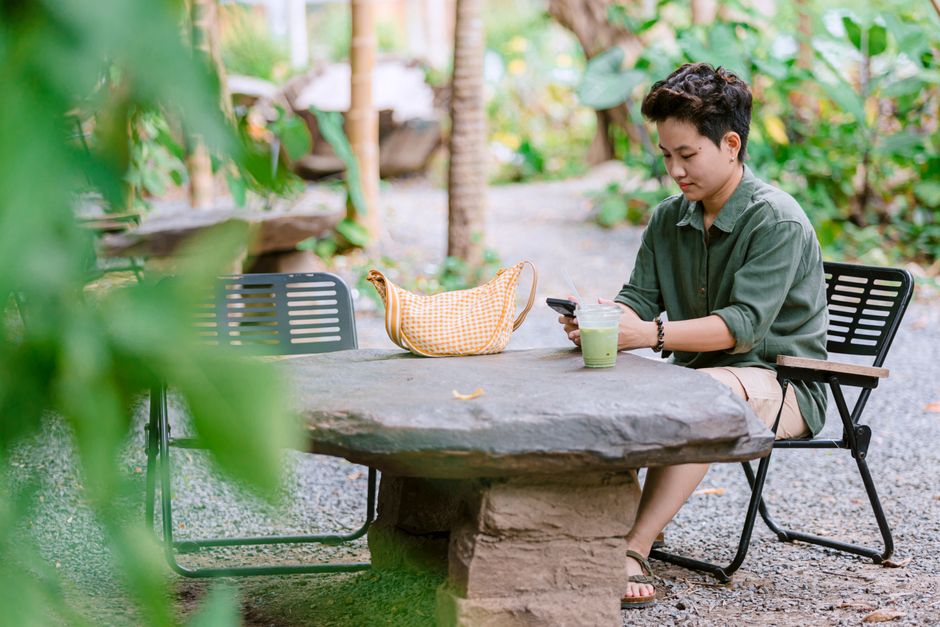 A traveler in a European cafe using the secure strap of an anti-theft bag to lock it to a chair, preventing grab-and-run theft.