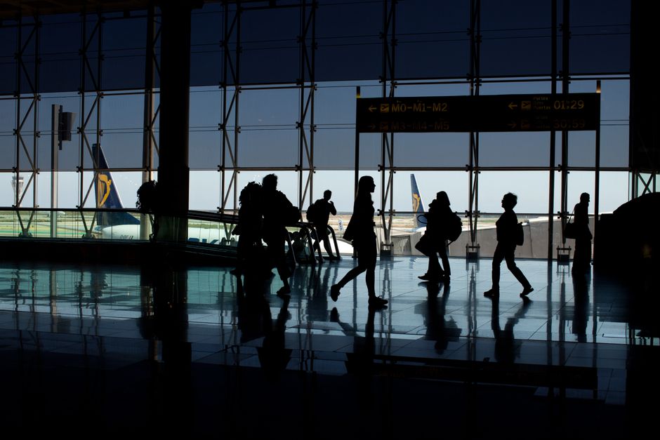 A traveler sitting at an airport gate, with a carry-on bag at their feet, illustrating compact travel.