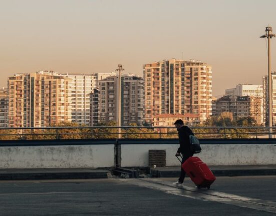 A person walking happily on a sunny city street, wearing comfortable, practical sneakers and carrying a backpack, with historic buildings in the background.