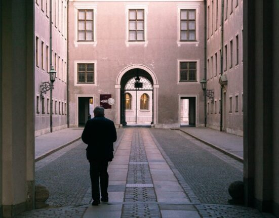 Traveler's feet in comfortable walking shoes navigating ancient European cobblestone street.