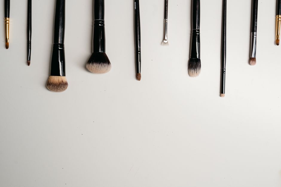 A flat lay of essential low-maintenance makeup items: tinted moisturizer, concealer, brow gel, mascara, and a lip/cheek tint, showing simplicity.