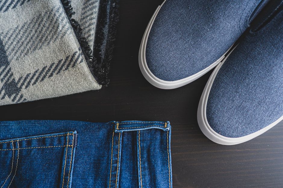 An overhead flat lay of different women's jean styles including skinny, straight-leg, and wide-leg jeans in various washes (dark, mid, light blue) on a neutral background.