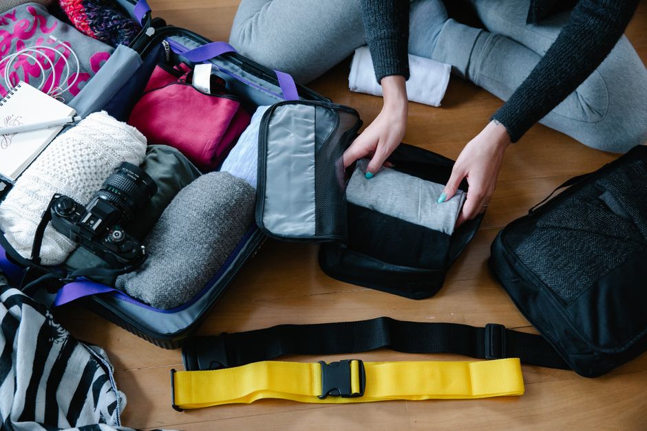 An organized display of various small travel bags: a personal item backpack, a crossbody bag, and a sleek laptop messenger bag, with travel essentials visible.
