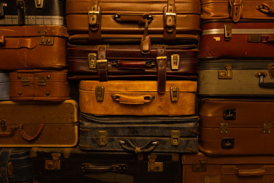 A collection of neatly stored travel and work bags, including leather and fabric types, organized on shelves in a closet, showing good storage practices.