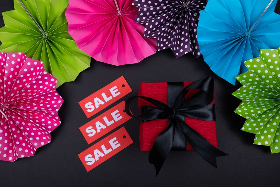 A flat lay of diverse, useful gift items like a smart water bottle, a sleek power bank, quality headphones, and a gourmet coffee set, all appearing to be on sale.