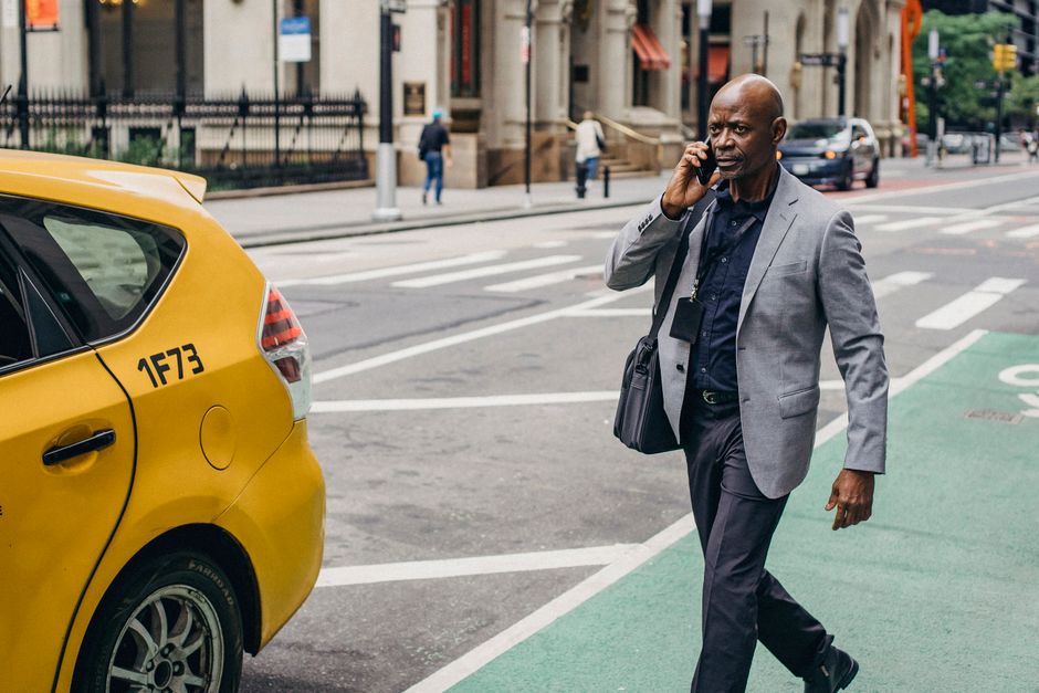 A stylish man in a classic overcoat and trousers walking confidently down a busy European city street.