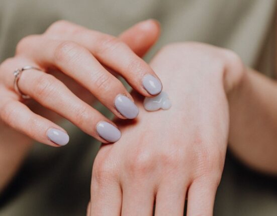Woman gently applying a hydrating moisturizer to her sensitive face, emphasizing a simple skin barrier routine.