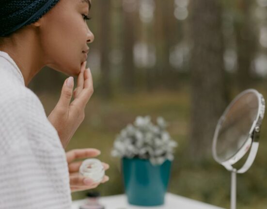 Woman gently applying a fragrance-free moisturizer to her face, emphasizing a simple and practical skincare routine.