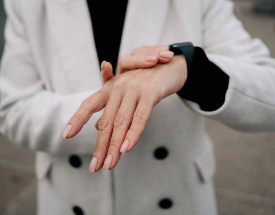 A woman examining the veins on her wrist in bright natural light to determine her skin's undertone, focusing on a practical beauty and skincare guide.
