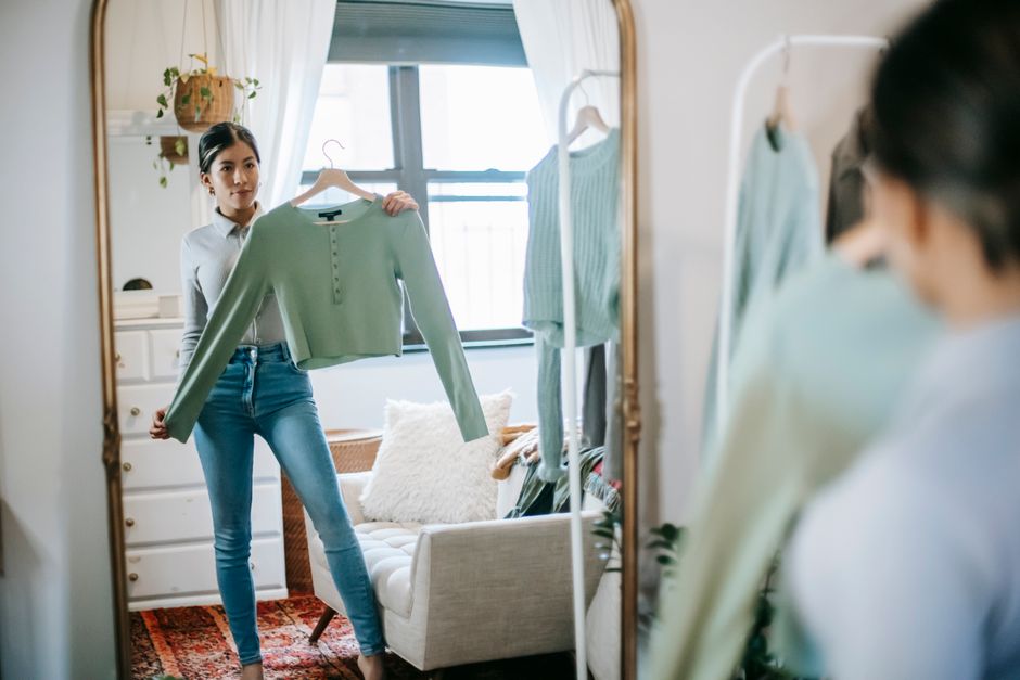 A busy woman in a stylish home reaching into an open closet, selecting a versatile dress, surrounded by a thoughtfully curated and compact wardrobe.