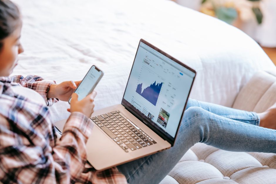 A woman's hands comparing different brand size charts on a laptop screen, highlighting the importance of measurements for online jean shopping.