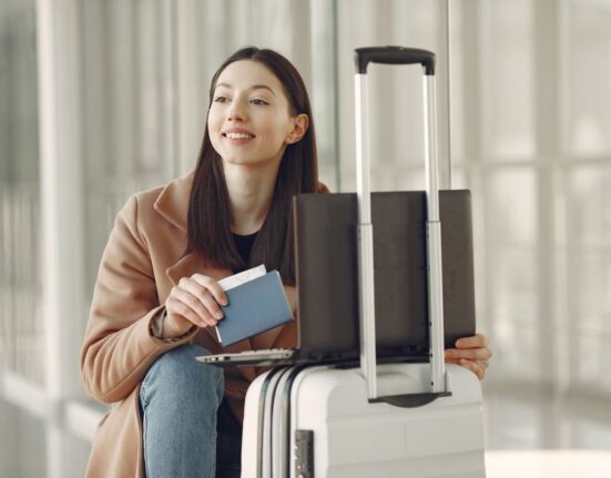 Woman thoughtfully comparing travel deals on a laptop screen, with multiple tabs open for flights and hotels, symbolizing careful research.