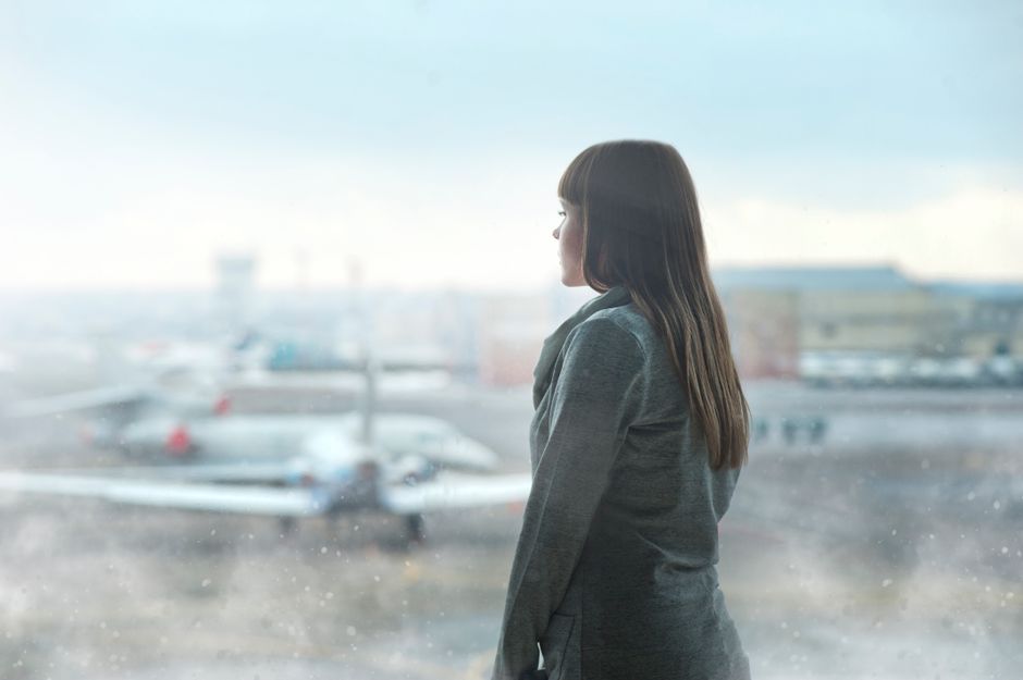 A person holding a glass of water on an airplane, emphasizing the importance of internal hydration during long-haul travel for skin health.