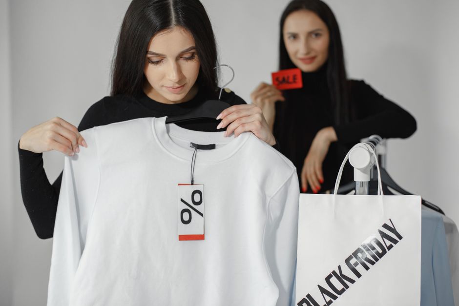A woman using a tablet to browse fashion items while a notification on her phone indicates a price drop.